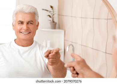 Happy senior man near mirror in bathroom - Powered by Shutterstock