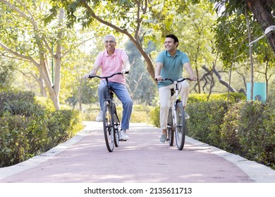 Happy senior man riding bicycle with his young son at park
