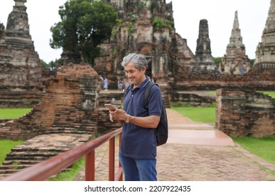 Happy Senior Man Searching Ancient Tourist Attraction From Internet Mobile Phone, Elderly Man Visited Ayutthaya Historical Park,Thailand.concept Older Adult Lifestyle,life,travel,ecotourism