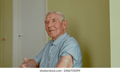 Happy senior man sitting in the doctor's office and showing his arm with adhesive plaster