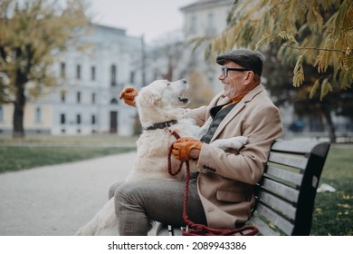 Happy senior man sitting on bench and resting during dog walk outdoors in city. - Powered by Shutterstock