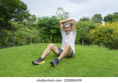 Happy Senior Man Sitting On Lawn And Cooling Down After Workout, Older Adult Resting In The Park Among Nature Atmosphere,concept Elderly People Lifestyle, Workout, Healthcare, Wellbeing