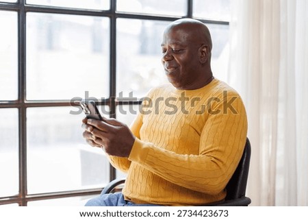 Happy Senior man smiling and using mobile phone while sitting in workplace.
