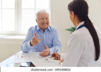 Happy senior man talking to doctor during visit to hospital office, thanking her for quick painless recovery. Clinician filling out medical history form while listening to old patient during interview - Powered by Shutterstock