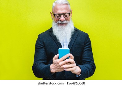 Happy Senior Man Using Smartphone App With Fluorescent Color In Background - Hipster Old Guy Having Fun With Technology - Tech And Joyful Elderly Concept - Focus On His Face