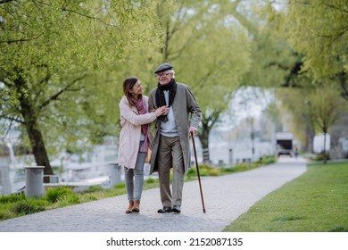 Happy senior man with walking stick and adult daughter outdoors on a walk in park. - Powered by Shutterstock