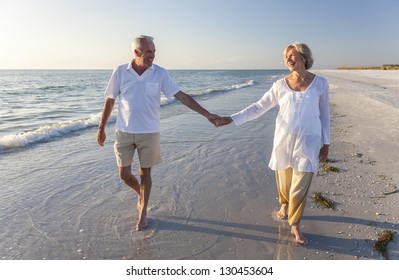 Happy senior man and woman couple walking and holding hands on a deserted tropical beach with bright clear blue sky, s3niorlife - Powered by Shutterstock