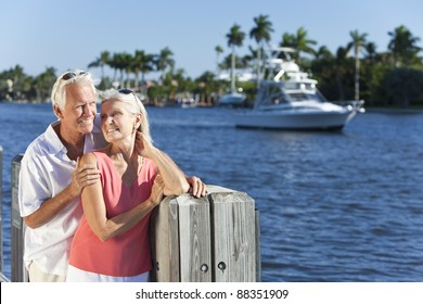 Happy Senior Man And Woman Couple Together By A River Or Sea In A Tropical Location With A Boat Sailing Past