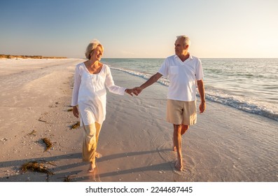 Happy senior man and woman old retired couple walking and holding hands on a beach at sunset, s3niorlife - Shutterstock ID 2244687445