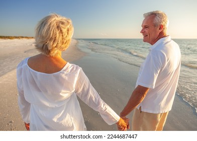 Happy senior man and woman old retired couple walking and holding hands on a beach at sunset, s3niorlife - Powered by Shutterstock