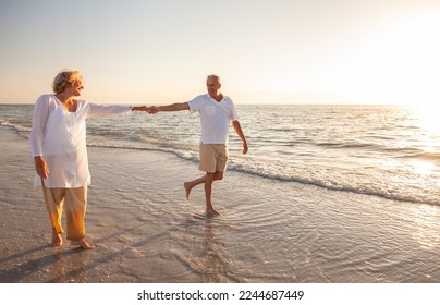 Happy senior man and woman old retired couple walking and holding hands on a beach at sunset, s3niorlife - Shutterstock ID 2244687449
