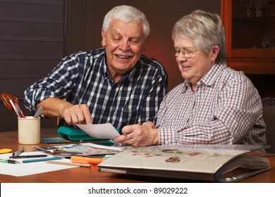 Happy Senior Married Couple Sharing Memories While  Working On Family Photo  Album Together. Horizontal Format.