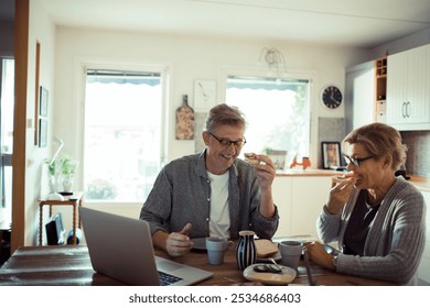 Happy senior mature couple laughing while eating at kitchen table - Powered by Shutterstock