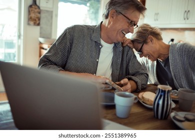 Happy senior mature couple laughing while eating at kitchen table - Powered by Shutterstock