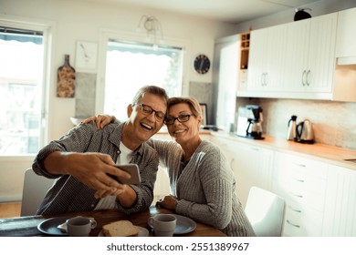 Happy senior mature couple laughing while eating at kitchen table - Powered by Shutterstock