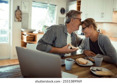 Happy senior mature couple laughing while eating at kitchen table - Powered by Shutterstock