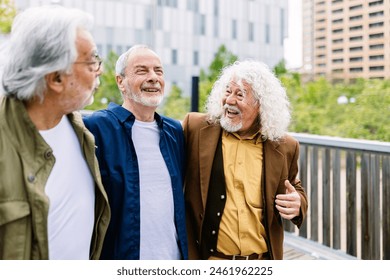 Happy senior men having fun together walking outdoors. Three older male friends laughing while enjoying a walk at city street. Mature friendship and retired people concept. - Powered by Shutterstock