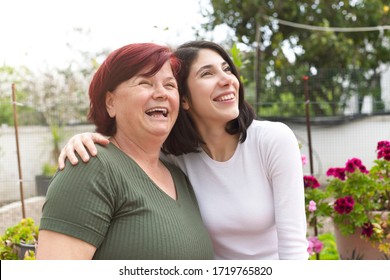 Happy Senior Mother And Adult Daughter Are Hugging. Happy Mother Daughter In The Garden Of Their Home In Quarantine.