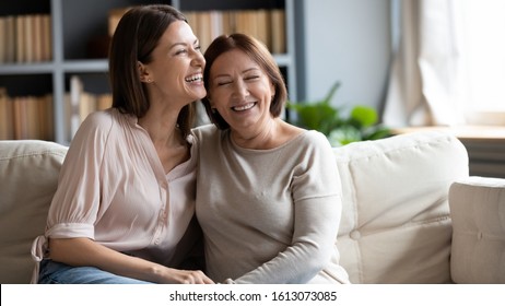 Happy senior mother and grownup daughter sit relax on couch in living room talk laugh and joke, smiling overjoyed middle-aged mom and adult girl child rest at home have fun enjoying weekend together - Shutterstock ID 1613073085