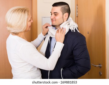 Happy Senior Mother Helping Adult Son To Tie A Scarf 