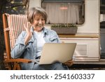 Happy senior old elderly caucasian woman freelancer grandmother talking on videocall webinar, vlogging blogging online on laptop with webcam while traveling by trailer motor home