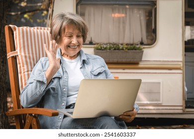 Happy senior old elderly caucasian woman freelancer grandmother talking on videocall webinar, vlogging blogging online on laptop with webcam while traveling by trailer motor home - Powered by Shutterstock