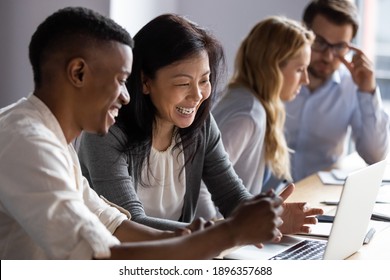 Happy senior old korean businesswoman discussing online project on laptop with african american male colleague, working together in pairs at shared workplace, analyzing electronic documents. - Powered by Shutterstock