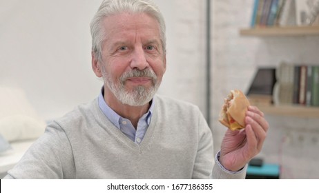 Happy Senior Old Man Eating Cheese Burger