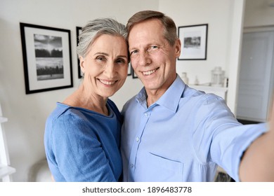 Happy senior older 50s couple hugging having fun looking at camera, holding phone taking selfie, shooting vlog or having virtual chat video call at home, close up headshot portrait, camera view. - Powered by Shutterstock