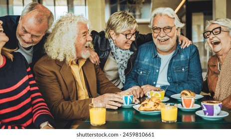 Happy senior people having breakfast sitting at coffee bar - Group of older friends having fun in rooftop restaurant - Life style concept with smiling men and women at cafe terrace - Powered by Shutterstock