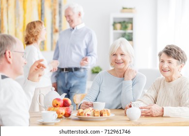 Happy senior people spending afternoon together at nursing home sitting at table and drinking tea  - Powered by Shutterstock