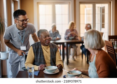 Happy senior people and their caregiver talking in dining room at nursing home. - Shutterstock ID 2189378971