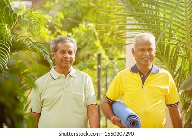 Happy Senior People With Yoga Mat In Park - Healthy Elderly Men With Fitness Mat Outdoor - Older Joyful Friends Walking In Garden During Morning.