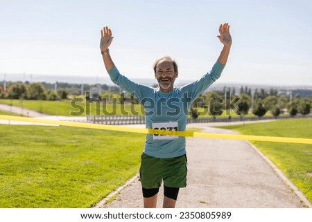 Happy senior running across the finish line - Mature man running marathon race. -
