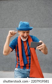 Happy Senior Sports Fan Cheering While Watching Soccer Match On Mobile Phone. Copy Space.