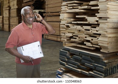 Happy Senior Warehouse Worker Talking On Mobile Phone