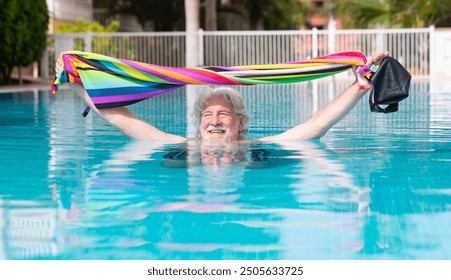 Happy senior white haired man getting out of outdoor swimming pool holding towel, swimming cap and goggles. Caucasian retired man enjoying healthy and active life - Powered by Shutterstock