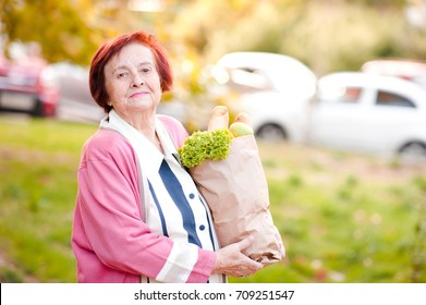 Happy Senior Woman 70-80 Year Old Holding Package With Food Posing Outdoors. Looking At Camera. Healthy Lifestyle. 