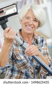 Happy Senior Woman Before Vacuum Cleaning House