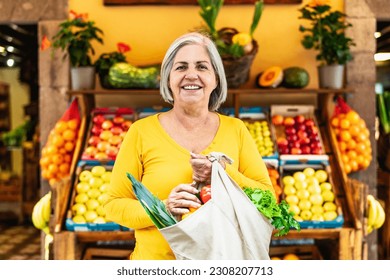 Happy senior woman buying fruits and vegetables at the market - Shopping food concept - Powered by Shutterstock