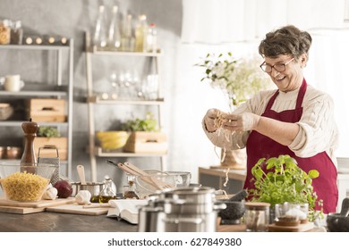 Happy senior woman cooking in her modern kitchen - Powered by Shutterstock