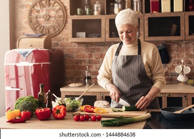 Happy Senior Woman Cooking In Modern Kitchen, Cutting Fresh Vegetables, Empty Space