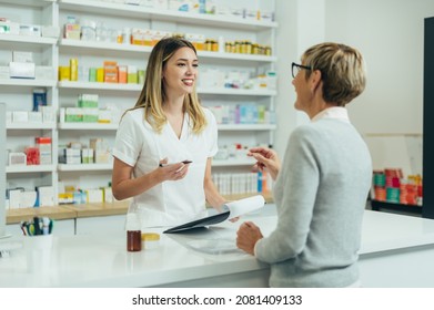 Happy senior woman customer buying medications at drugstore while talking with a female pharmacist