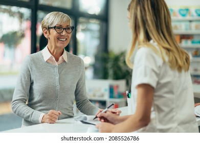Happy senior woman customer buying medications at drugstore while talking with a female pharmacist - Shutterstock ID 2085526786