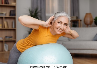 Happy Senior Woman Doing Exercises With Fitness Ball At Home, Training Her Back Muscles With Sports Equipment During Domestic Workout, Lady Looking And Smiling At Camera