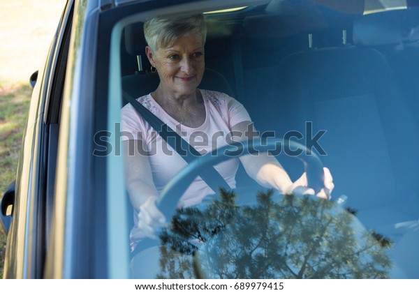 Happy senior woman driving a\
car
