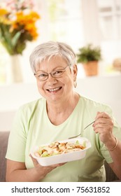 Happy Senior Woman Eating Healthy Salad At Home. Looking At Camera, Smiling.?