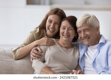 Happy senior woman enjoying warm good relationship with adult daughter and loving older husband, posing with family for shooting, looking away, smiling, laughing - Powered by Shutterstock