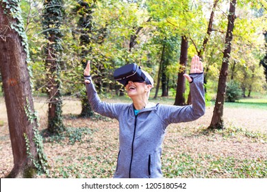 Happy Senior Woman Fun With Virtual Reality Headset In Forest, VR Device Using Old People.