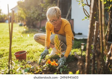 Happy senior woman gardening in her yard. She is is planting a flower.	 - Powered by Shutterstock